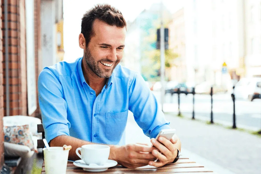 Smiling man relaxing at an outdoor cafe table