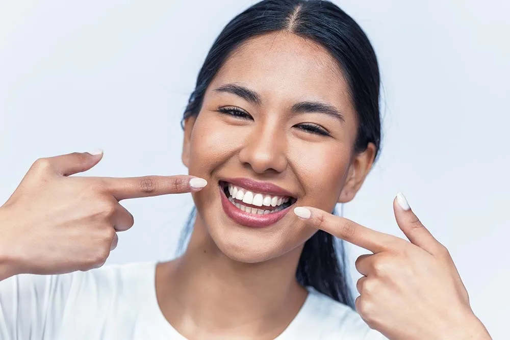 Smiling woman pointing to her bright smile