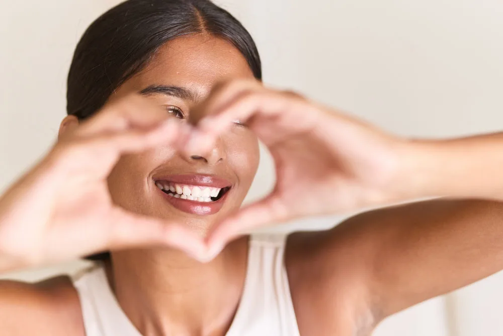 Smiling woman forming a heart shape with her hands near her face